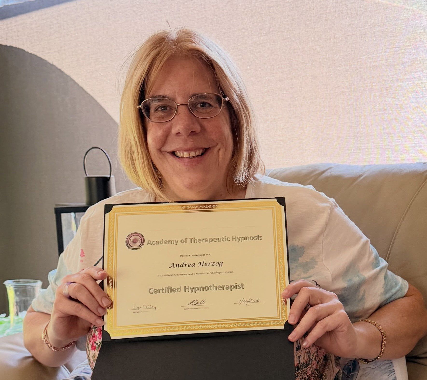 Andrea Herzog smiling and holding her Certified Hypnotherapist certificate