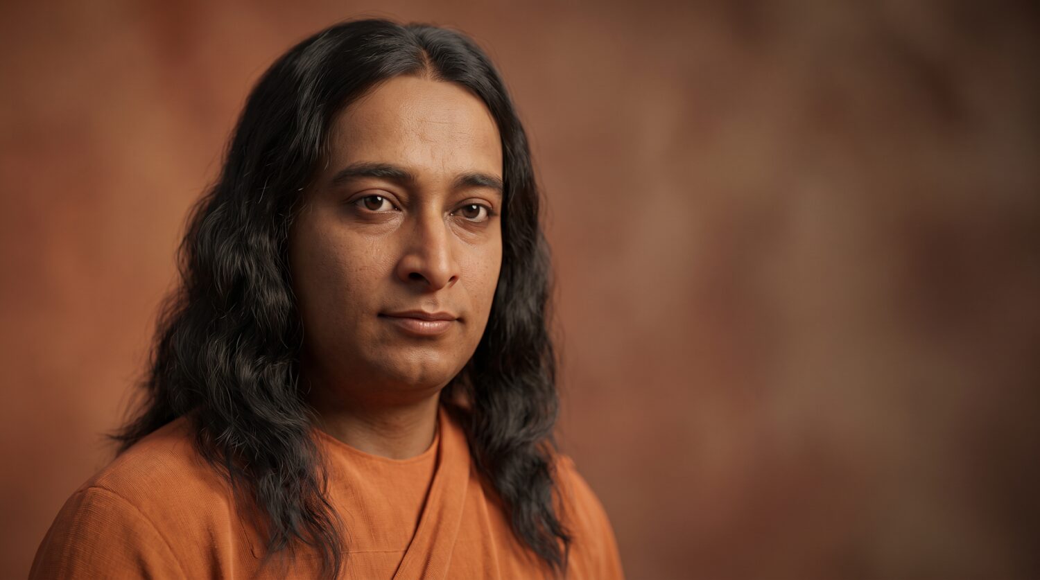 A young Paramahansa Yogananda with long wavy hair in a saffron robe