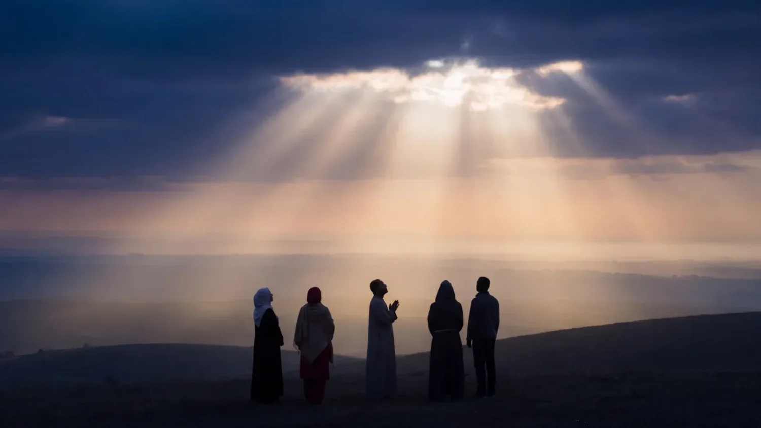 Golden light opening in an indigo twilight sky over silhouettes of people of many faiths standing together